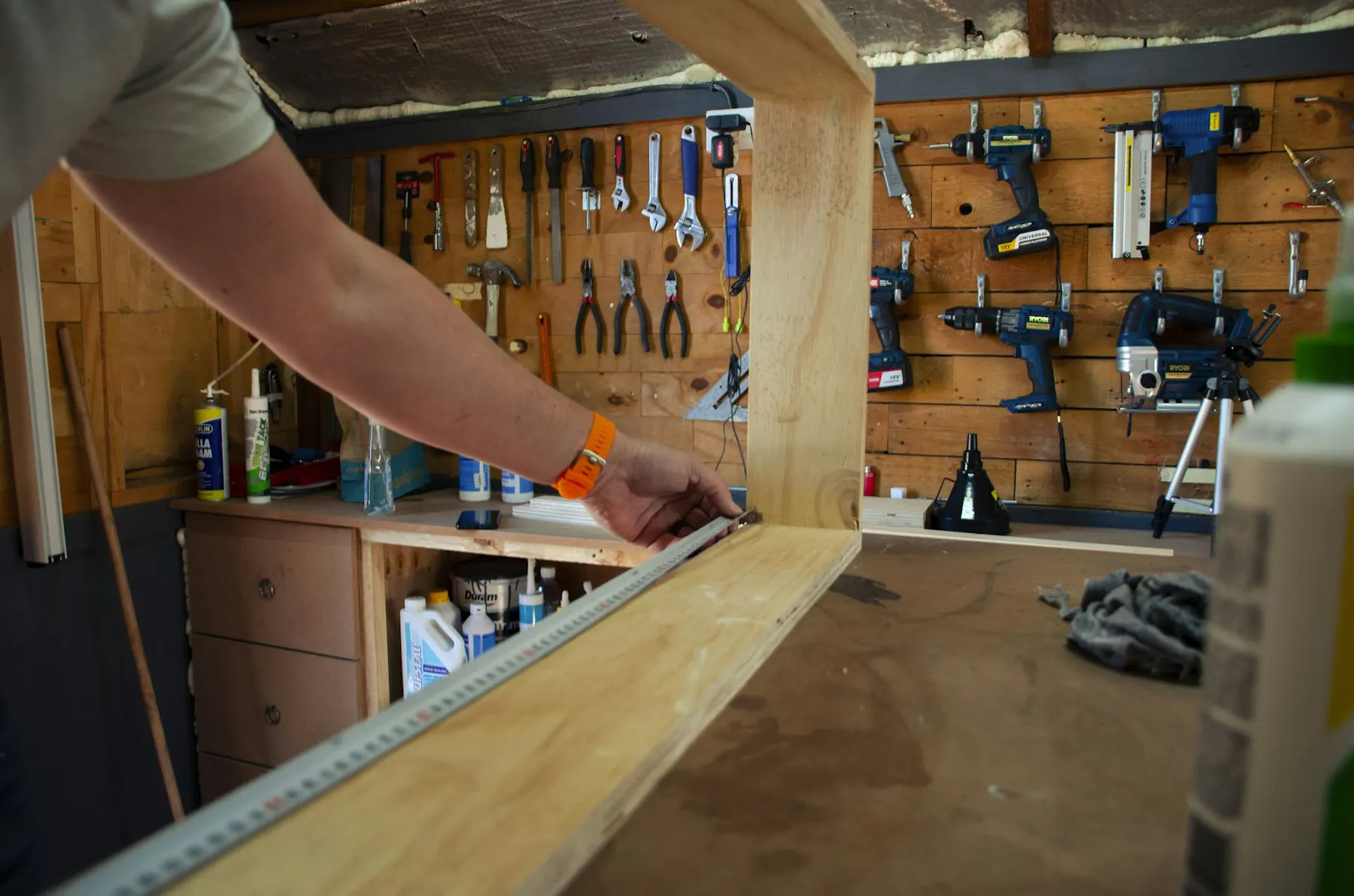 Timmerman meet een houten plank af in de werkplaats