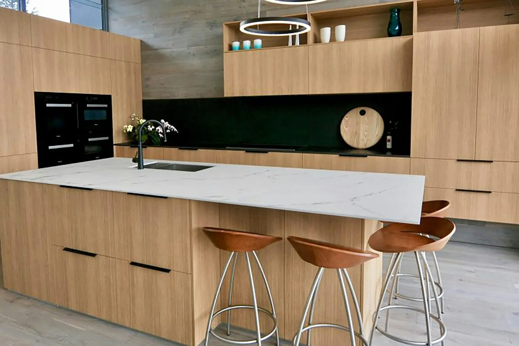 Keuken met houten fronten, wit werkblad en barkrukken aan het eiland